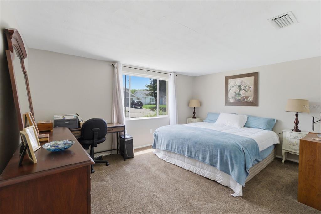 A bedroom features a bed with blue bedding, a desk, and a wooden dresser — 12219 QUAIL RUN ROW, BAYONET POINT, FL