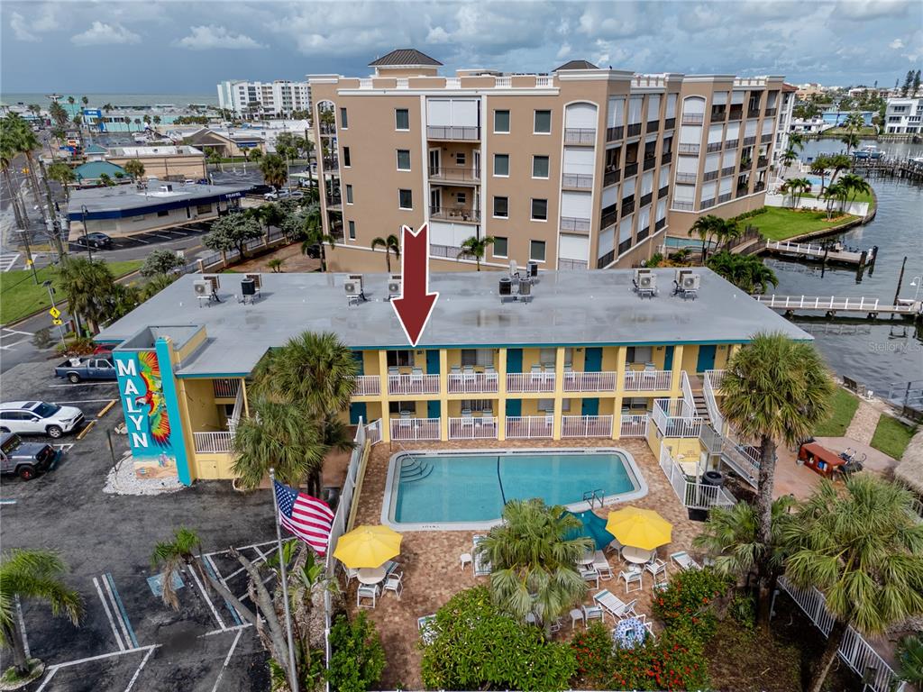 An aerial view shows a two-story motel with a pool, parking lot, and waterfront access — 282 TREASURE ISLAND CAUSEWAY UNIT 12, TREASURE ISLAND, FL