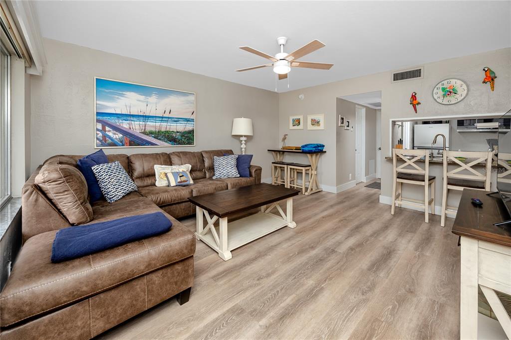 A living room features a brown sectional sofa, a coffee table, and an open kitchen — 282 TREASURE ISLAND CAUSEWAY UNIT 12, TREASURE ISLAND, FL