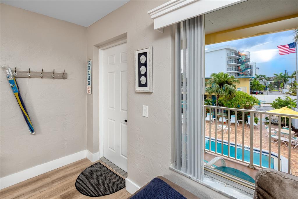 A room with a door, a wall-mounted coat rack, and a window overlooking a pool — 282 TREASURE ISLAND CAUSEWAY UNIT 12, TREASURE ISLAND, FL