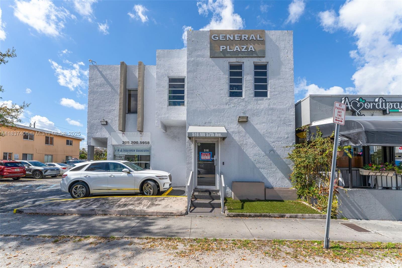 A white two-story commercial building with a parking lot and a sidewalk in front — 516 NW 57th Ave, Miami FL 33126, MIAMI, FL
