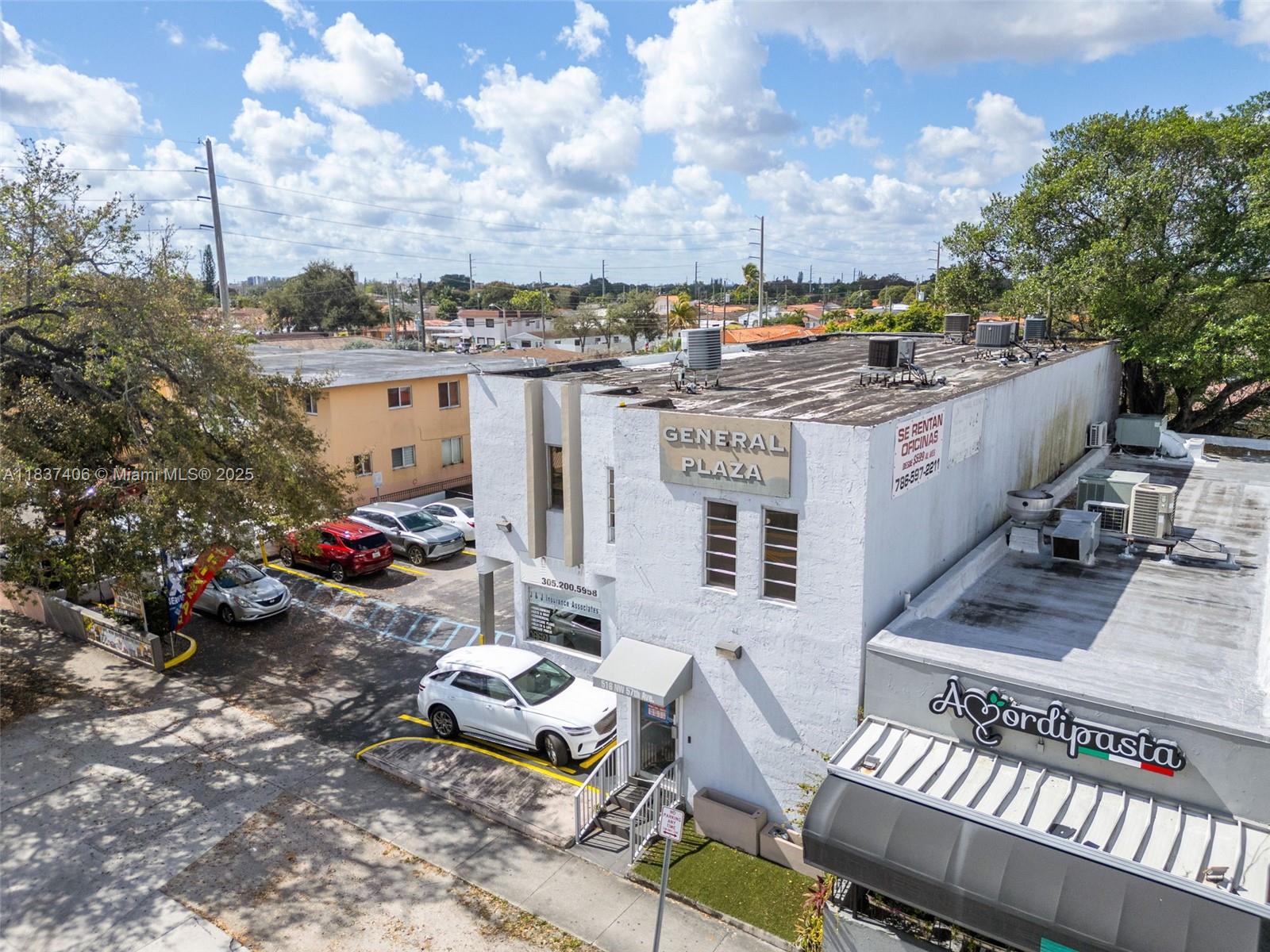An aerial view shows a white commercial building with a parking lot and surrounding trees — 516 NW 57th Ave, Miami FL 33126, MIAMI, FL