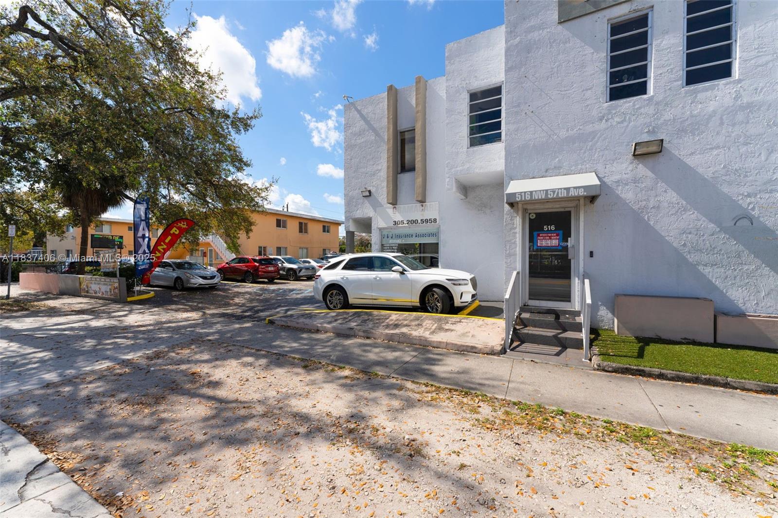 A white two-story commercial building features a parking lot with several cars in front — 516 NW 57th Ave, Miami FL 33126, MIAMI, FL