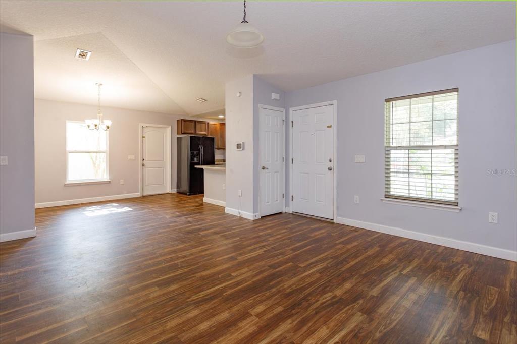 An open-concept living and dining area features wood-look flooring and light-colored walls — 1241 3RD STREET, ORANGE CITY, FL