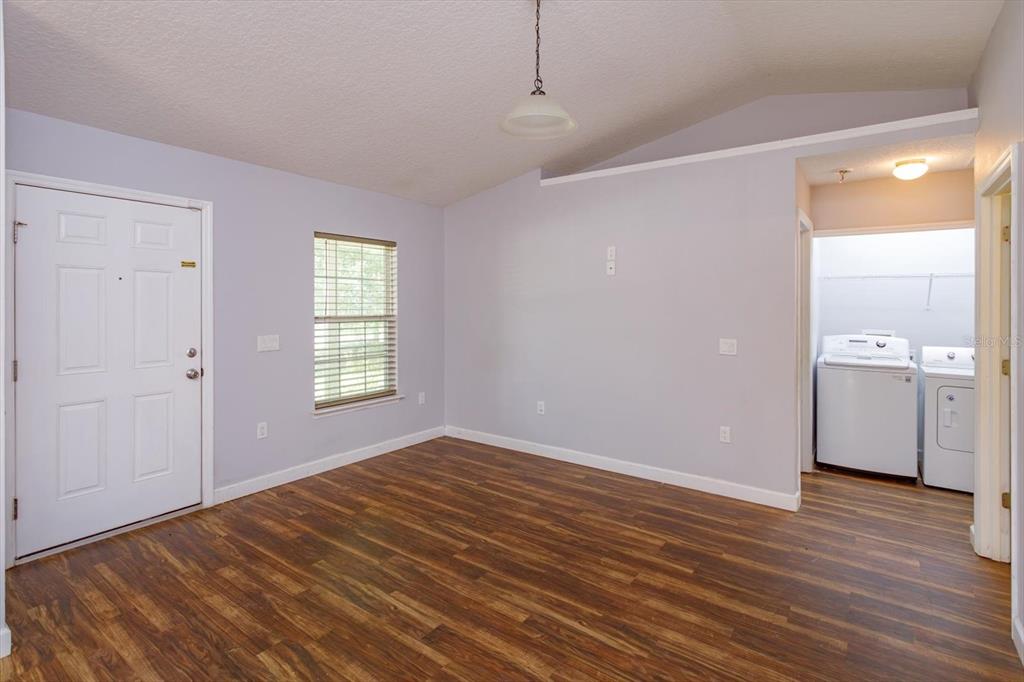 A room with wood-look flooring, light gray walls, a window, and an adjacent laundry area — 1241 3RD STREET, ORANGE CITY, FL
