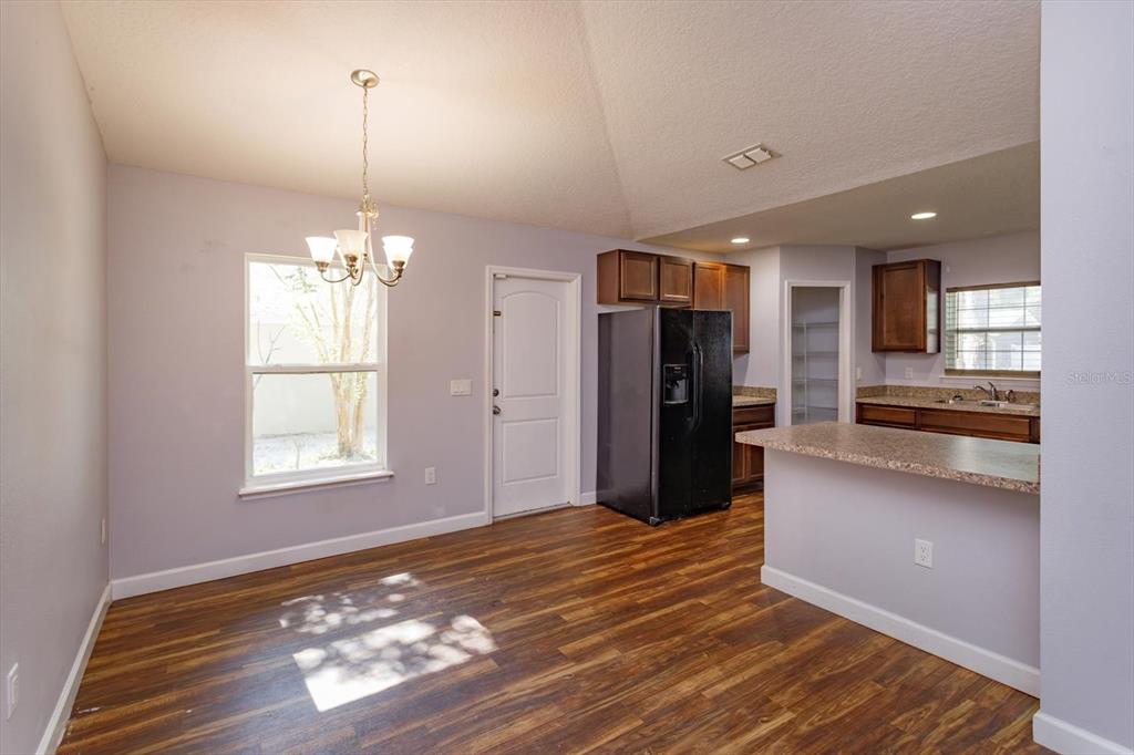 A dining area with wood-look flooring, a chandelier, and an adjacent kitchen with dark cabinets — 1241 3RD STREET, ORANGE CITY, FL