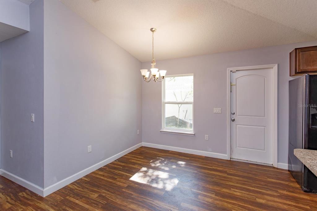 A dining area with wood-look flooring, a chandelier, a window, and a white door — 1241 3RD STREET, ORANGE CITY, FL