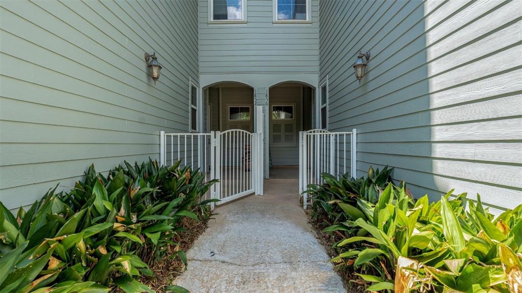 A concrete walkway leads to two gated entrances of a light green siding building — 1852 NW 34TH STREET UNIT 24, GAINESVILLE, FL