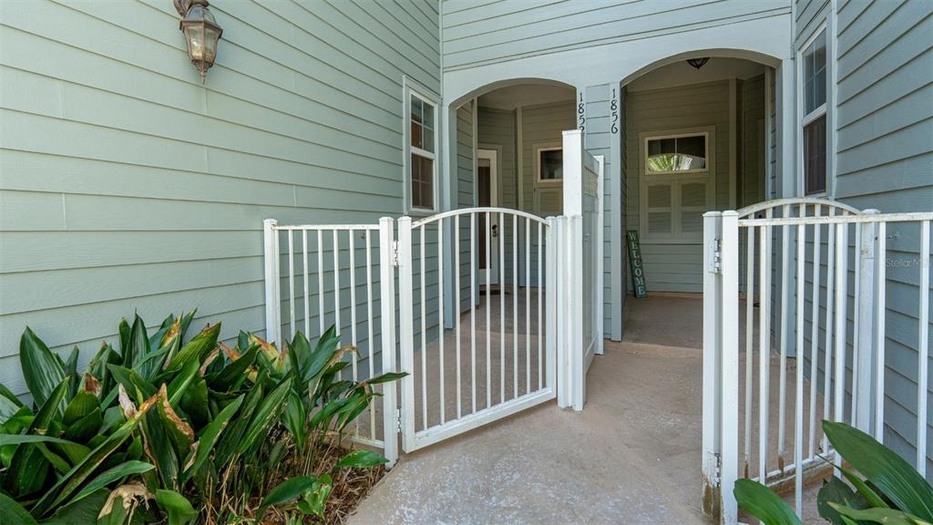 A gated entrance leads to two separate doorways with house numbers on a light blue exterior — 1852 NW 34TH STREET UNIT 24, GAINESVILLE, FL