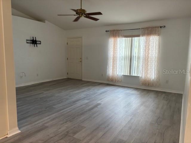 An empty living room features light gray wood-look flooring, a ceiling fan, and a window — 1707 W BEACH PLUM DRIVE, CITRUS SPRINGS, FL
