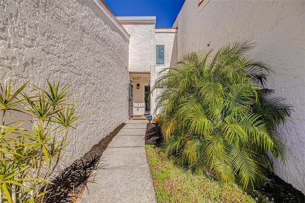 A concrete walkway leads to the front entrance between two textured white stucco walls — 4316 SUNRAY COURT UNIT 34, TAMPA, FL