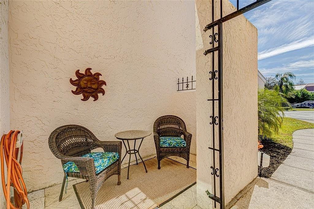 A small outdoor patio features two wicker chairs, a small table, and a sun wall decoration — 4316 SUNRAY COURT UNIT 34, TAMPA, FL
