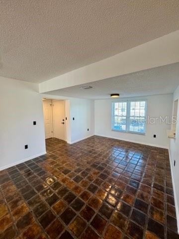 An empty room features dark, square-tiled flooring, white walls, and a window with blinds — 2462 KINGFISHER LANE UNIT J203, CLEARWATER, FL