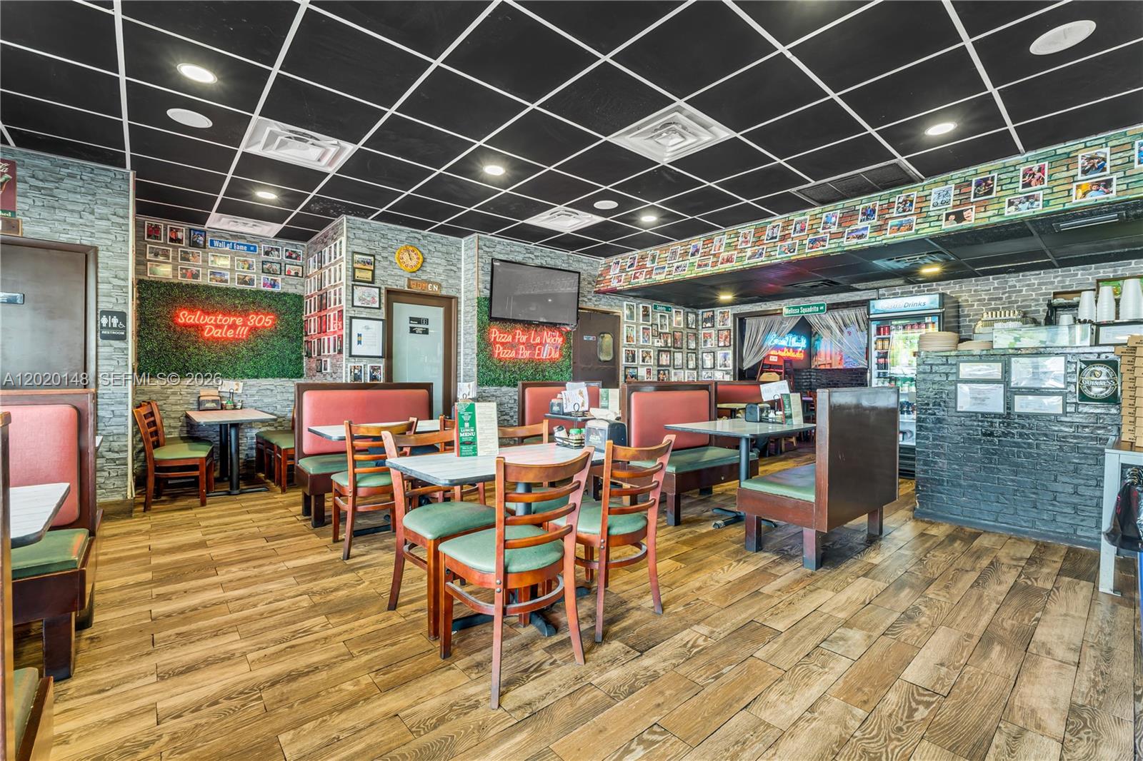 A restaurant interior features wooden floors, booth seating, tables, and a black grid ceiling — W 84 St, Hialeah FL 33014, HIALEAH, FL