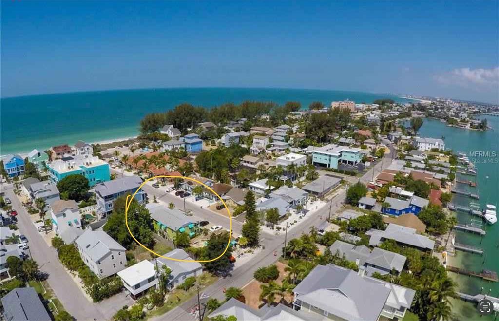 An aerial view shows a coastal neighborhood with a yellow-circled house near the beach — 61 81ST AVENUE UNIT 2, TREASURE ISLAND, FL