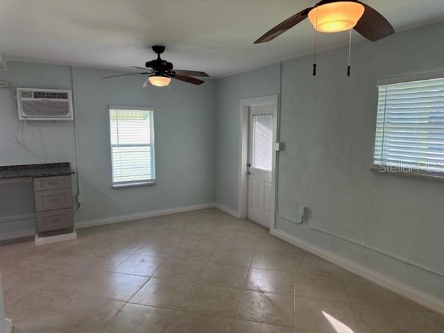 An interior room features light blue walls, tile flooring, two ceiling fans, and two windows — 61 81ST AVENUE UNIT 2, TREASURE ISLAND, FL