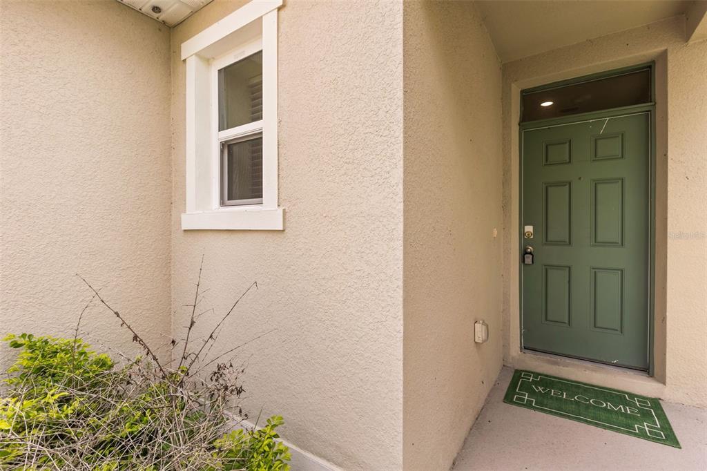 A green front door with a transom window sits beside a window on a stucco exterior — 289 GINA LANE, DAVENPORT, FL