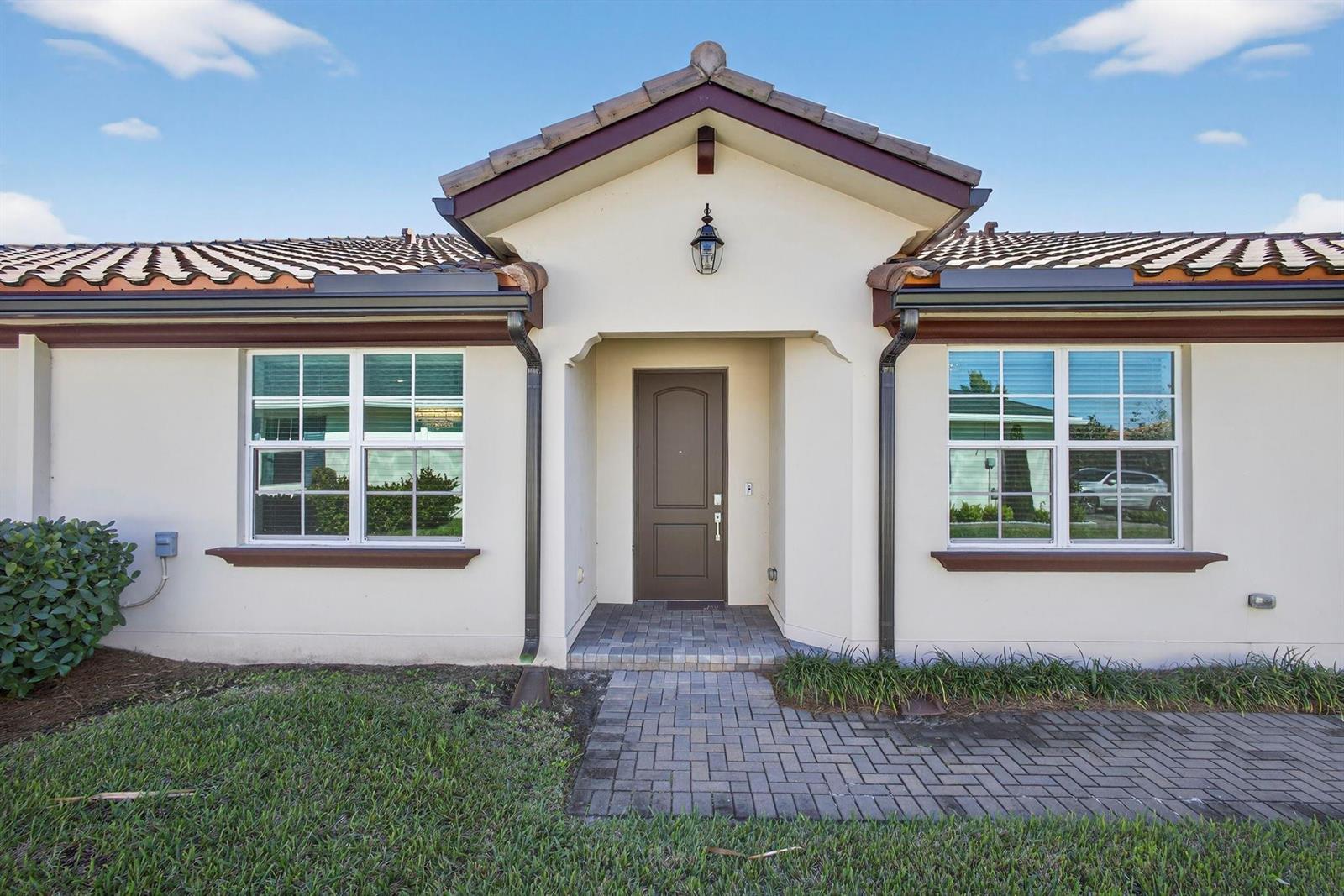 The exterior of a house features a brown front door, tiled roof, and brick walkway — 1232 Haywagon Trail # 0, Loxahatchee FL 33470, LOXAHATCHEE, FL