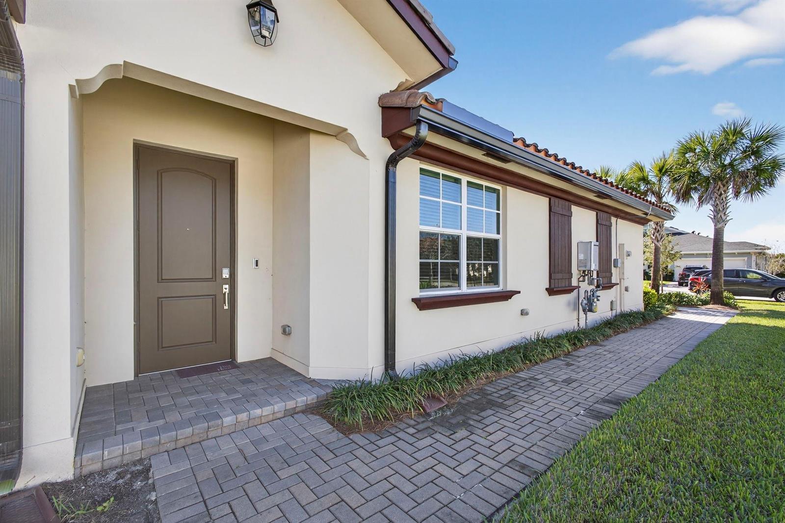 A paved walkway leads to the front entrance of a house with a brown door — 1232 Haywagon Trail # 0, Loxahatchee FL 33470, LOXAHATCHEE, FL