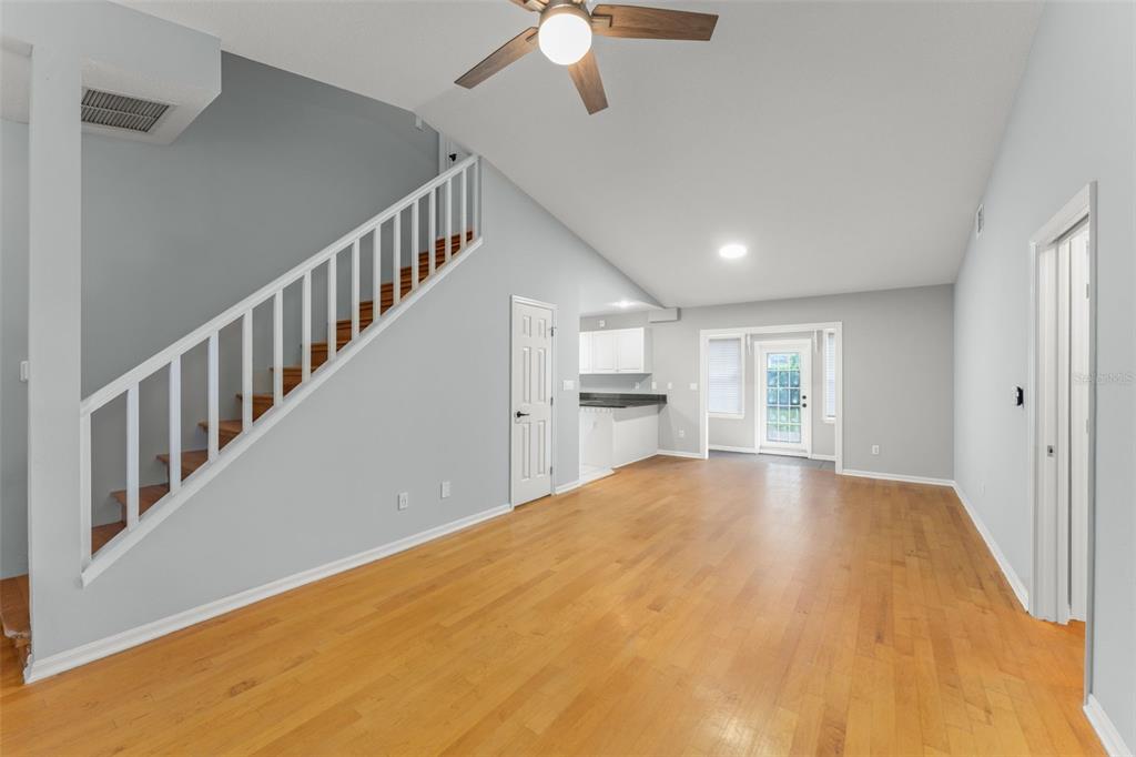An open living area features hardwood floors, a staircase with white railings, and a kitchen — 805 W SMITH STREET, ORLANDO, FL