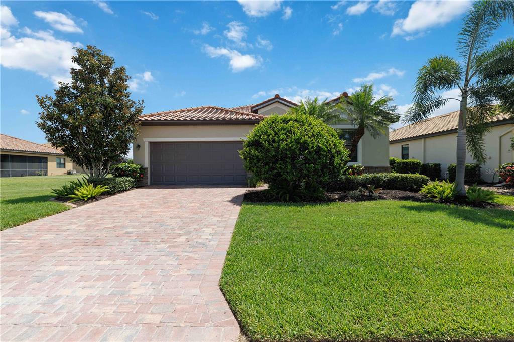 A single-story house with a paved driveway, a two-car garage, and a manicured lawn — 6907 QUIET CREEK DRIVE, BRADENTON, FL