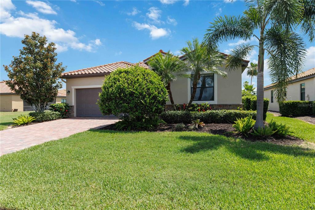 A single-story house with a paved driveway, a two-car garage, and palm trees — 6907 QUIET CREEK DRIVE, BRADENTON, FL