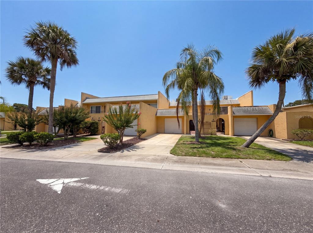 A row of yellow townhouses with attached garages and palm trees under a clear sky — 3538 DAIRY ROAD UNIT 0, TITUSVILLE, FL
