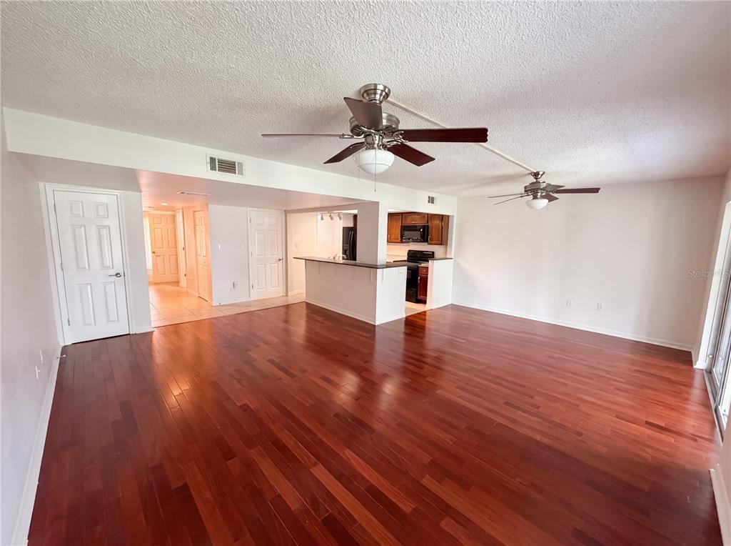 A living room with hardwood floors, two ceiling fans, and an open kitchen with a counter — 3538 DAIRY ROAD UNIT 0, TITUSVILLE, FL