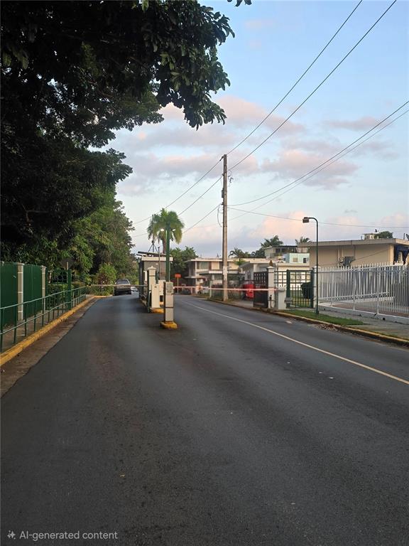 A gated entrance with a security booth and a lowered barrier arm on a paved road — 1608 TAMESIS apt. 201B, SAN JUAN, PR