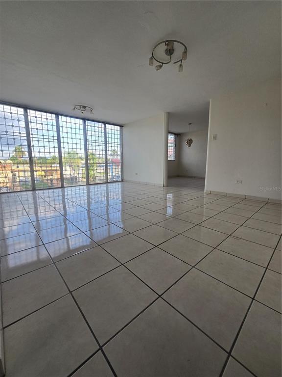 An empty room with large windows, security bars, and light-colored tiled flooring — 1608 TAMESIS apt. 201B, SAN JUAN, PR