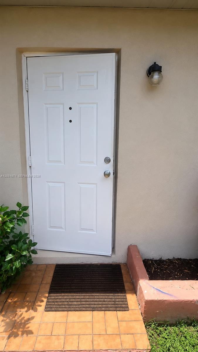 A white front door with two peepholes is set in a tan exterior wall — 8935 SW 28th St # 8935, Miami FL 33165, MIAMI, FL