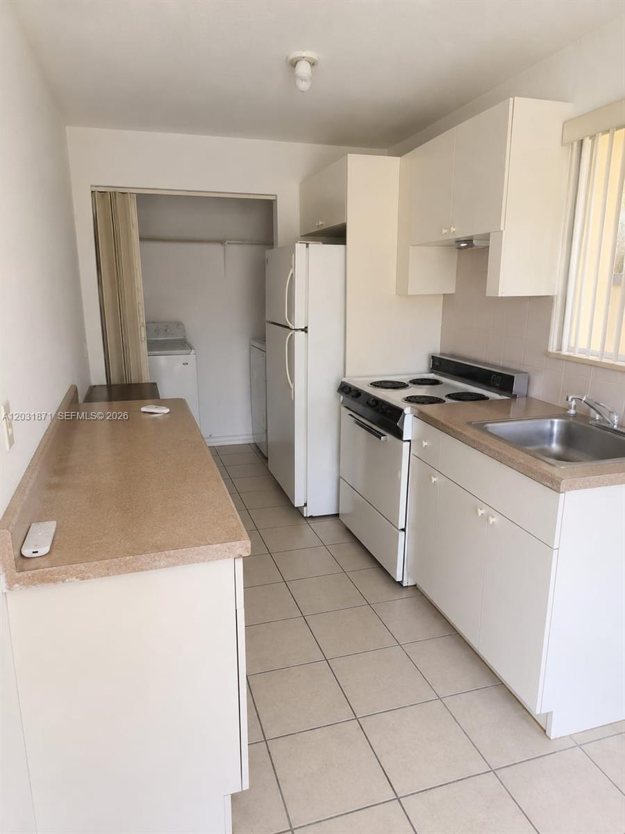 A kitchen features white cabinets, a white stove, a refrigerator, and a tiled floor — 8935 SW 28th St # 8935, Miami FL 33165, MIAMI, FL