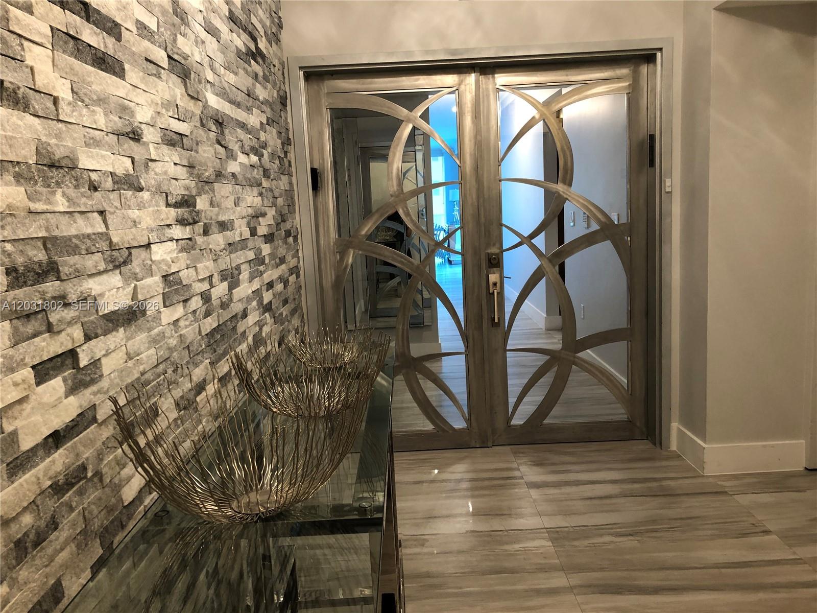 An entryway features a stone accent wall, a glass console table, and decorative double doors — 3101 S Ocean Dr # 801, Hollywood FL 33019, HOLLYWOOD, FL