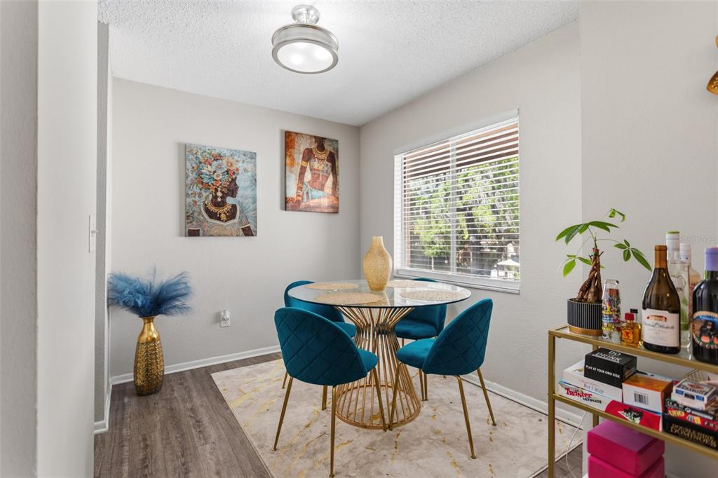 A dining room features a glass-topped table, teal velvet chairs, and two framed wall portraits — 7506 PRESLEY PLACE UNIT 113, TAMPA, FL
