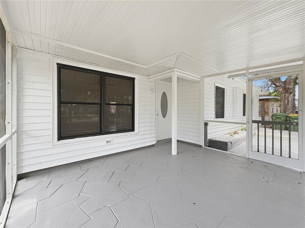 A covered, screened-in porch features gray patterned concrete flooring and white horizontal siding — 2847 OAK STREET, SARASOTA, FL