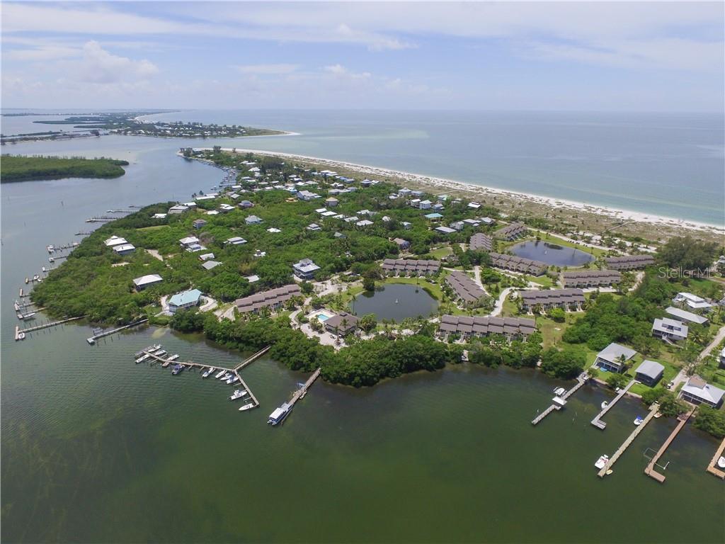 An aerial view shows a coastal residential complex with multiple buildings, a pond, and docks — 9400 LITTLE GASPARILLA ISLAND UNIT A10, PLACIDA, FL