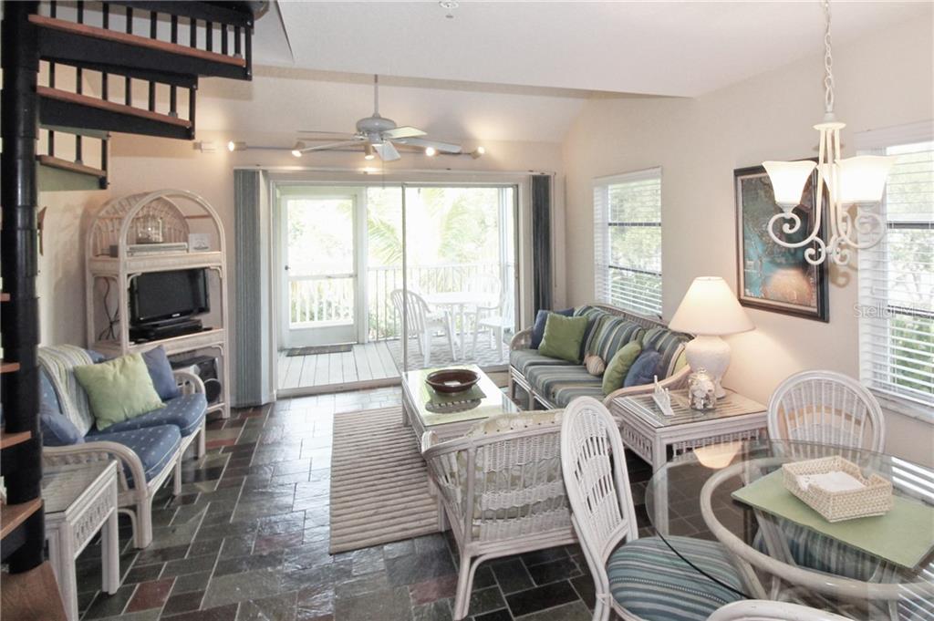 A living and dining area features slate tile floors, wicker furniture, and a spiral staircase — 9400 LITTLE GASPARILLA ISLAND UNIT A10, PLACIDA, FL