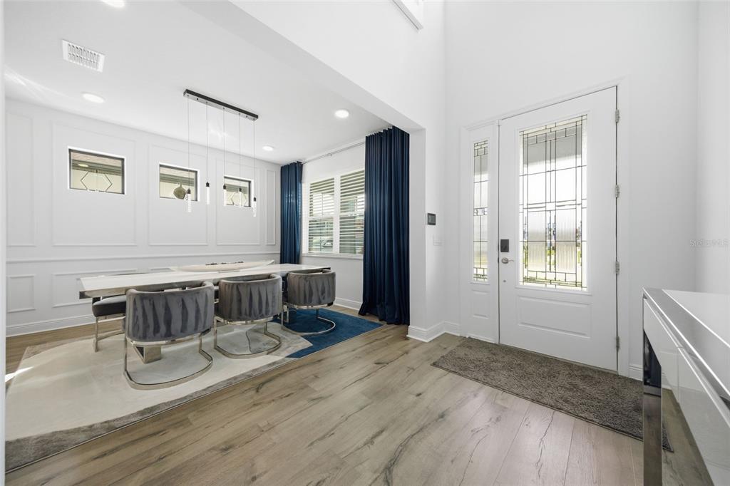 A dining room with a white table and grey chairs sits beside a front entryway — 7771 NOTCHED PINE BEND, WESLEY CHAPEL, FL