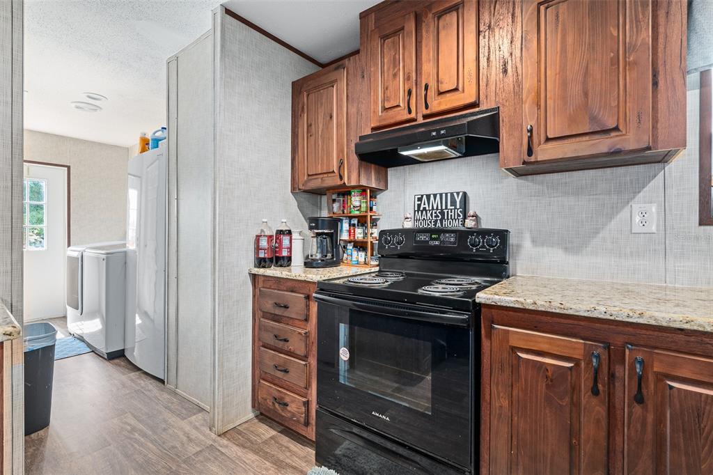 A kitchen features dark wood cabinets, granite countertops, a black stove, and a laundry area — 42215 BEECH AVENUE, DELAND, FL