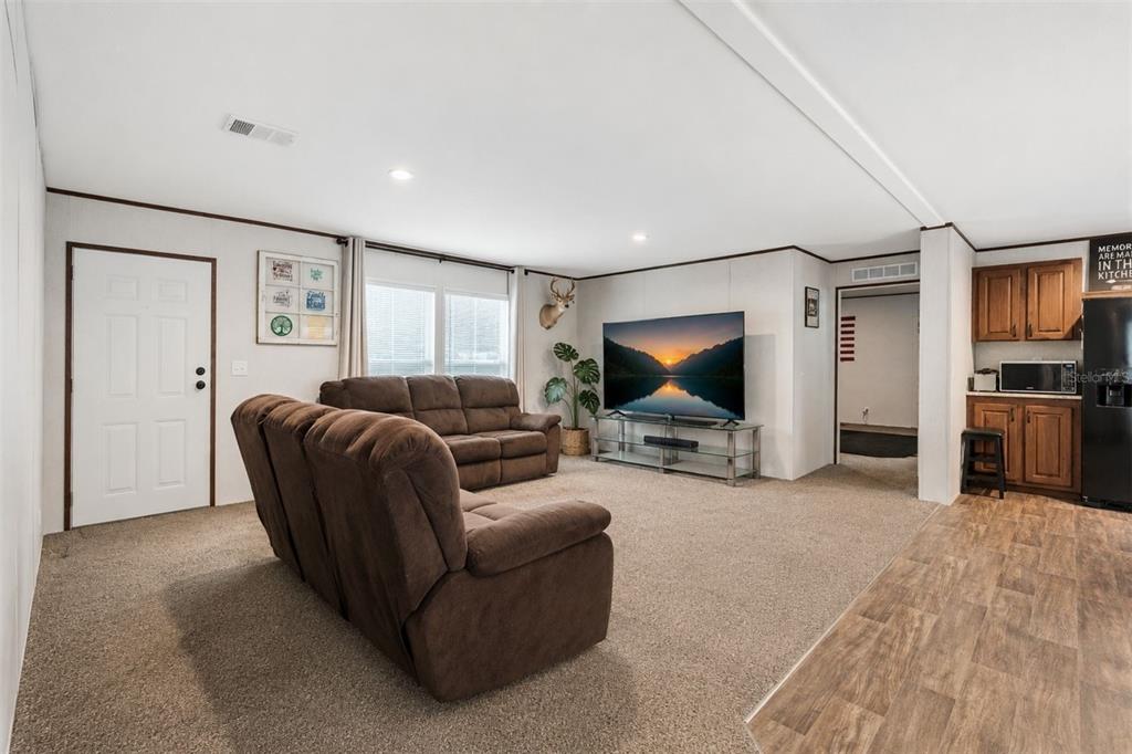 A living room with brown sofas, a television, and an adjacent kitchen area with cabinets — 42215 BEECH AVENUE, DELAND, FL