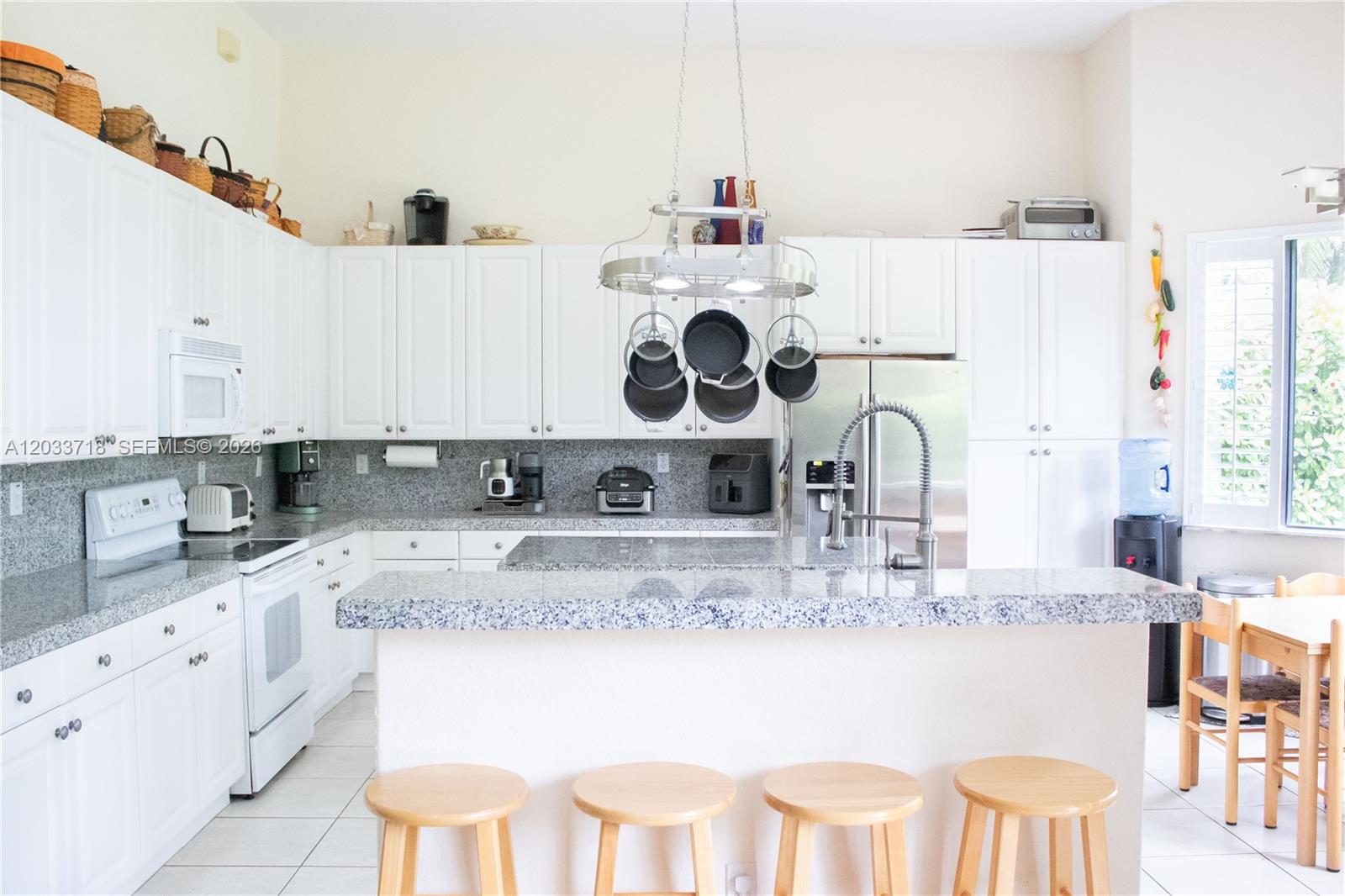 A kitchen features white cabinetry, granite countertops, a central island, and a hanging pot rack — 7645 SW 193rd Ln, Cutler Bay FL 33157, CUTLER BAY, FL