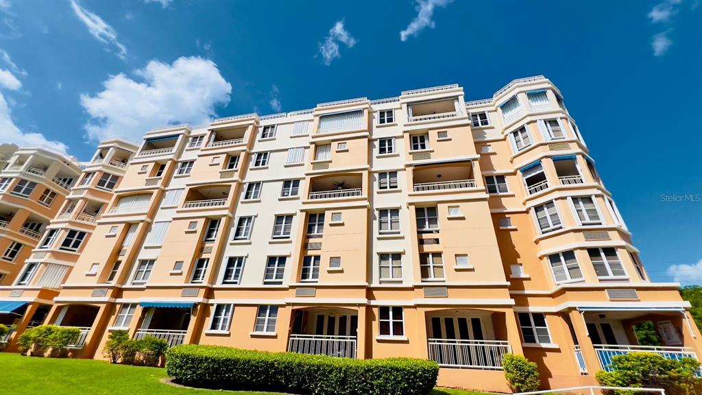 A low-angle exterior view of a multi-story, beige apartment building under a blue sky — 3 CARR 115 PLAYA ALMIRANTE UNIT PH 605B, ANASCO, PR