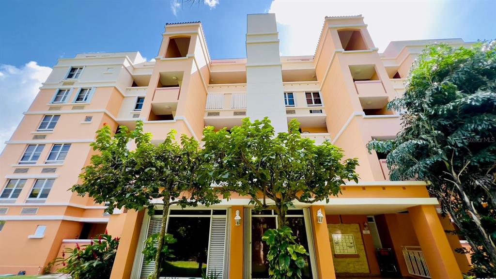 A low-angle exterior view of a multi-story peach-colored apartment building with balconies and trees — 3 CARR 115 PLAYA ALMIRANTE UNIT PH 605B, ANASCO, PR