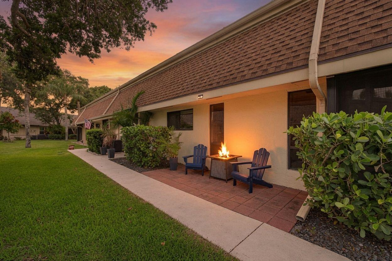 A patio with two blue chairs and a fire pit sits outside a residential building — 101 Half Moon Circle # C, Jupiter FL 33458, JUPITER, FL