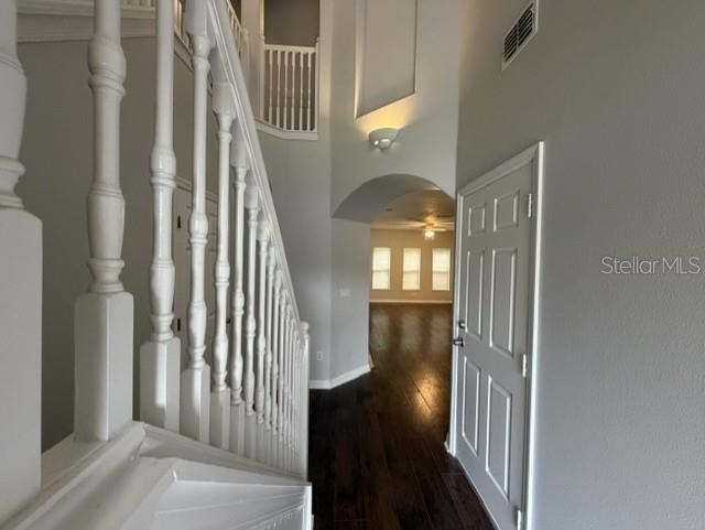 A white staircase railing leads to an entryway with dark wood floors and an arched opening — 6025 APOLLOS CORNER WAY, ORLANDO, FL