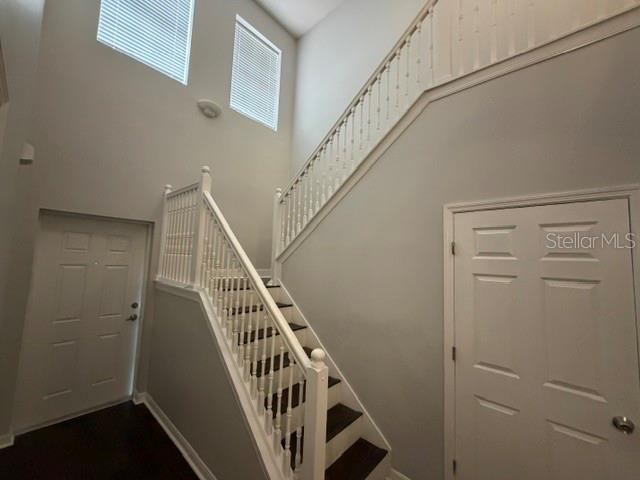 An interior view of a foyer featuring a staircase with white railings and two doors — 6025 APOLLOS CORNER WAY, ORLANDO, FL