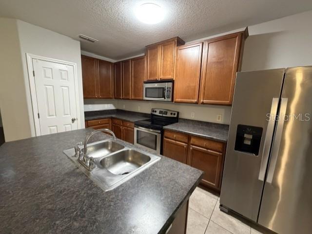 A kitchen features wood cabinets, dark countertops, stainless steel appliances, and a central island sink — 6025 APOLLOS CORNER WAY, ORLANDO, FL