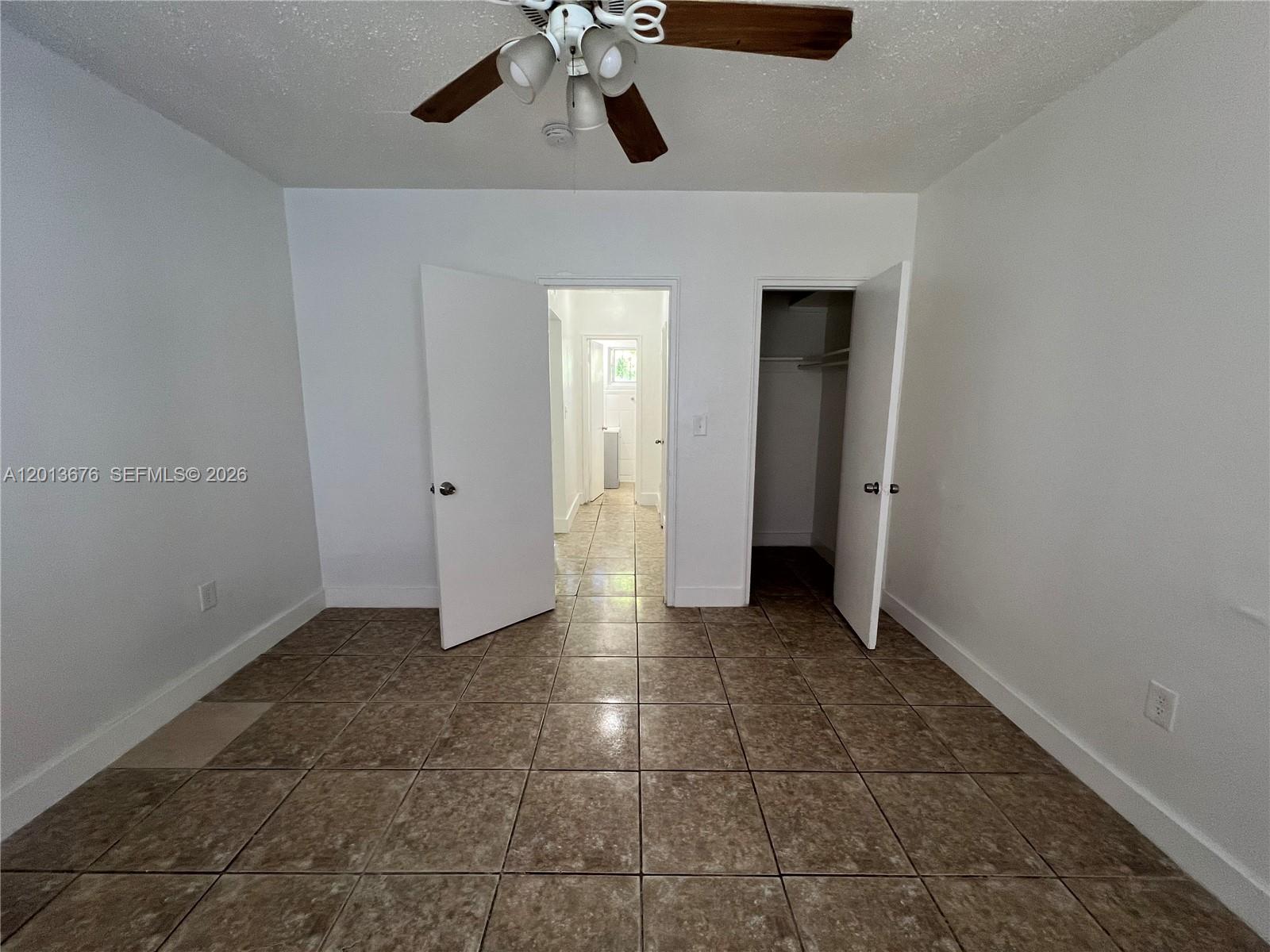 An empty room features white walls, brown tile flooring, a ceiling fan, and two doorways — 5600 NE 1st Ave # 2, Miami FL 33137, MIAMI, FL