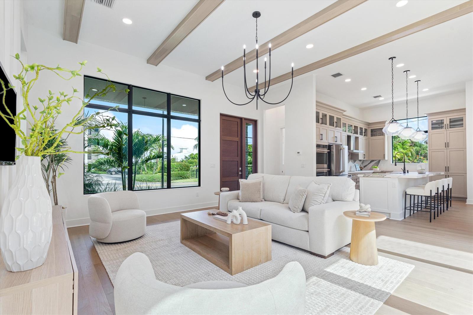 A bright, open-concept living room and kitchen featuring wood ceiling beams and large windows — 432 NW North River Drive, Stuart FL 34994, STUART, FL