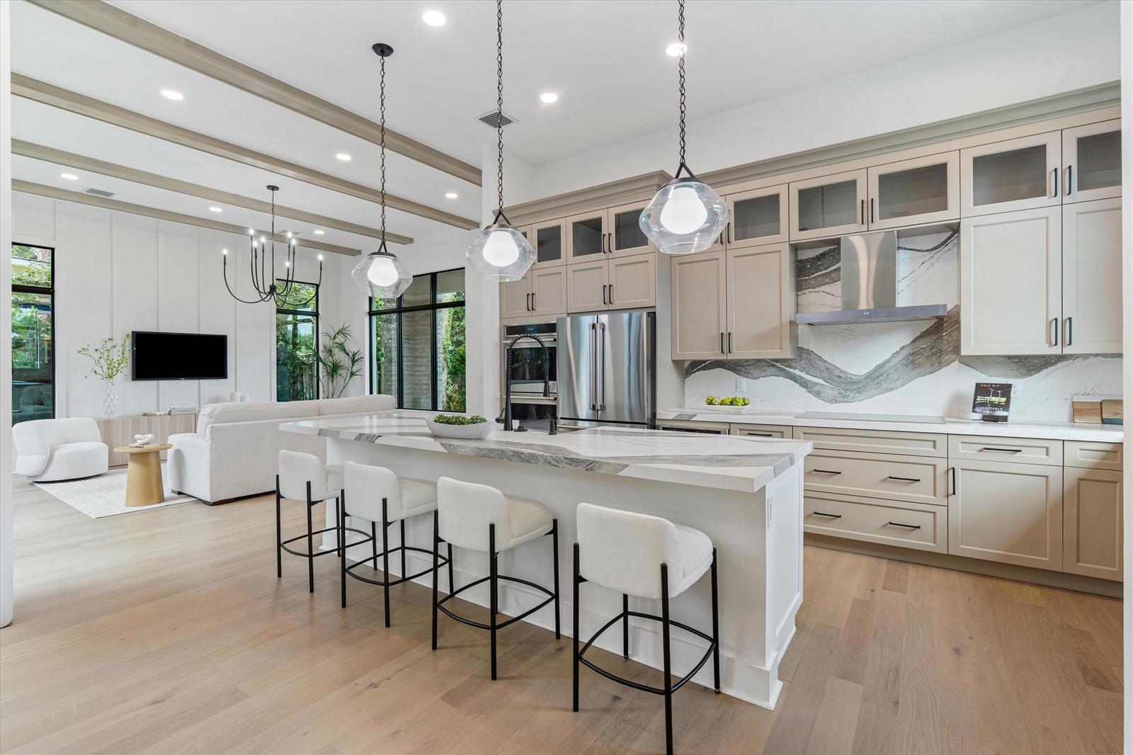 A modern kitchen features a large marble island, light wood floors, and beige cabinetry — 432 NW North River Drive, Stuart FL 34994, STUART, FL